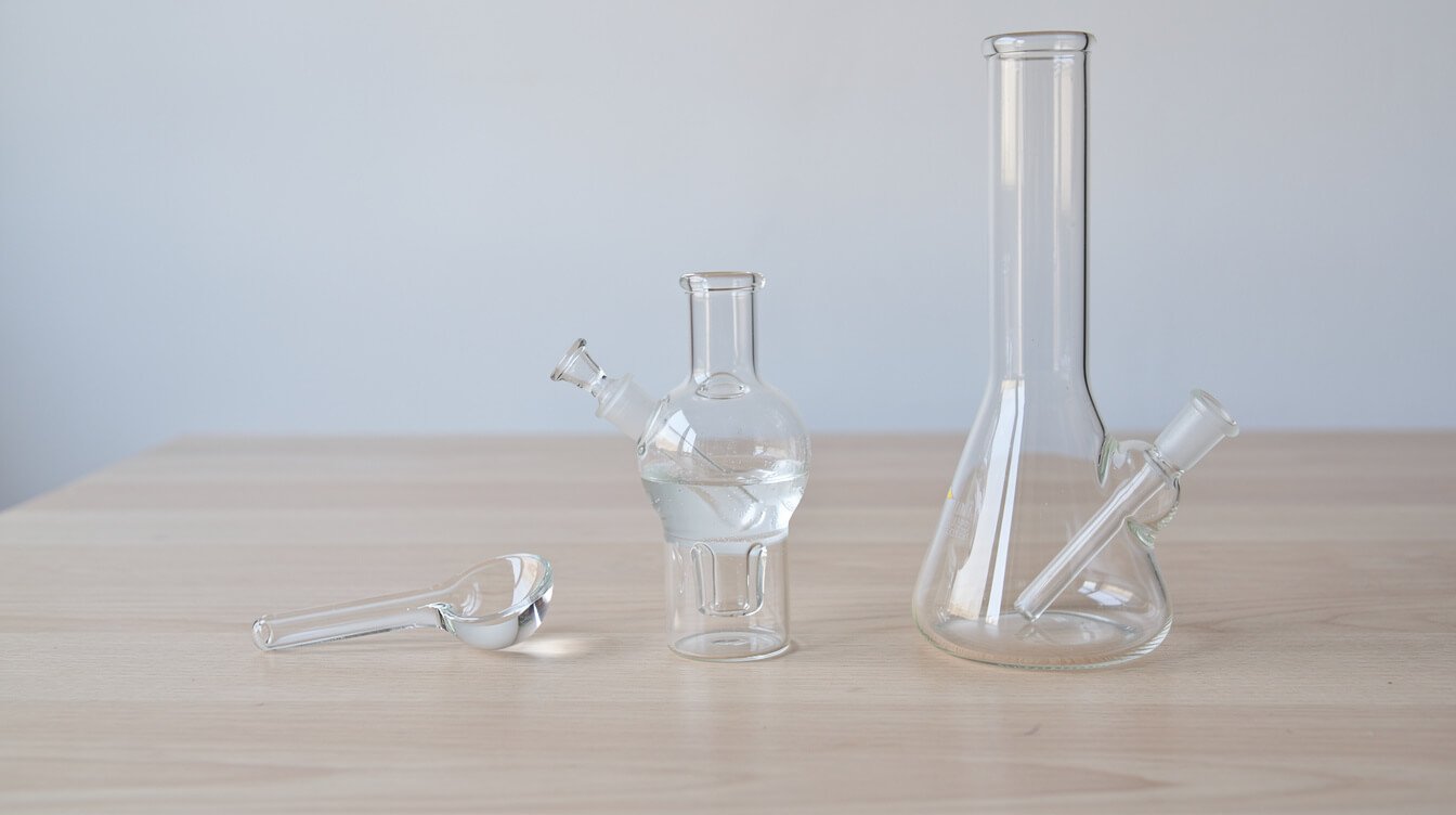 A dry glass hand pipe, a bubbler, and a bong side by side for size comparison